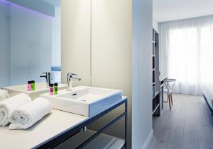 a white bathroom with a sink and towels on a counter at B&B Hotel Madrid Centro Puerta del Sol in Madrid