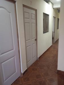 a hallway with a white door and a tile floor at Casa Hotel Lunita in Iquitos