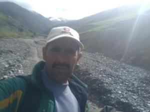 a man wearing a hat standing in front of a river at Sidi hssain in Amizmiz