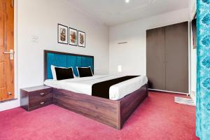 a bedroom with a large bed with a blue headboard at Hotel O Wave Inn in Srinagar +21 photos