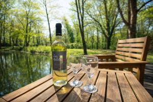 a bottle of wine and two glasses on a wooden table at Les Chalets Horizon in Saint-Just-de-Claix