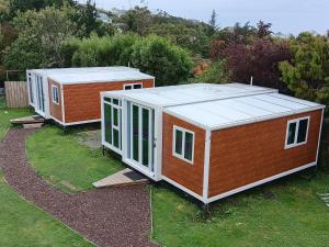 two tiny houses are sitting on the grass at Sleeps 3 to 4 - - 200m from beach in Dunedin