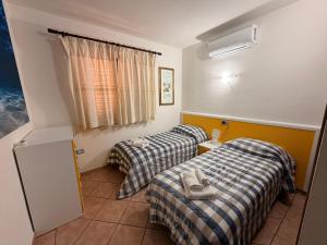 a hotel room with two beds and a window at Villa Pinna in San Teodoro