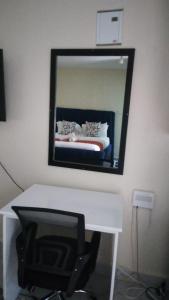 a mirror on a wall above a white desk with a bed at AA Suites 87 in Nairobi