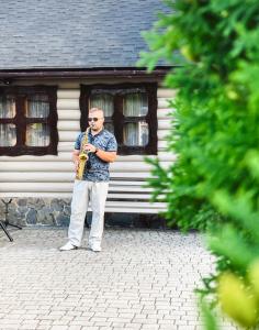 a man playing a saxophone in front of a building at Orlyne Gnizdo in Chernivtsi