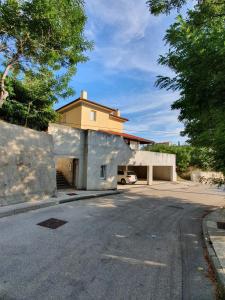 a building with a car parked in front of a driveway at Villa Dora - Mediterranean family house for 9 with private garden, BBQ, sea view and private parking for 4 cars in Pag
