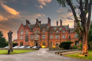 ein großes Backsteingebäude, vor dem Autos parkten in der Unterkunft Wroxall Abbey Hotel & Estate in Wroxall
