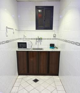 a kitchen with a sink and a microwave at فندق صفوة الجميزة in An Naqāʼ