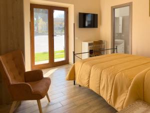 a bedroom with a bed and a chair and a sliding glass door at Casale Saporito in Montopoli in Sabina