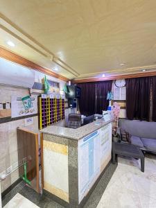 a kitchen with a counter and a living room with a couch at فندق صفوة الجميزة in An Naqāʼ
