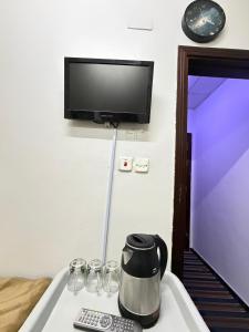 a room with a tv and a coffee pot and glasses at فندق صفوة الجميزة in An Naqāʼ