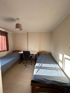 a room with two beds and a desk and a table at Spacious 3 bed semi-detached house in Luton