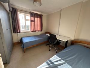 a bedroom with two beds and a desk in it at Spacious 3 bed semi-detached house in Luton