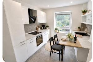 a kitchen with white cabinets and a table with chairs at Apartment Heide in Soltau
