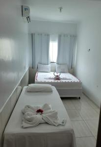 two beds in a white room with towels on them at Casa Maragogi 6 Quartos E Piscina in Maragogi