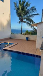 a swimming pool with a palm tree and the ocean at Casa Maragogi 6 Quartos E Piscina in Maragogi +5 photos