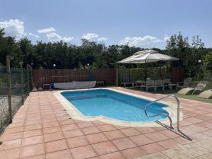 a swimming pool in a backyard with an umbrella at Zuchar in Granada