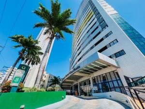 a tall building with a palm tree in front of it at Plaza Suíte Natal Vista Mar in Natal