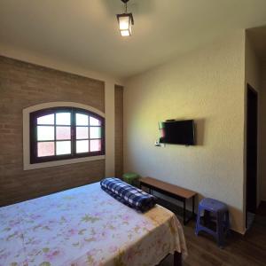 a bedroom with a bed and a flat screen tv at Pousada Cantinho das Fadas in Conceição da Ibitipoca