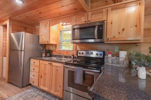 a kitchen with stainless steel appliances and wooden cabinets at Ryon Tiny Home Cabin City-side Rustic Retreat in Chattanooga