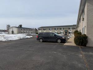 a black car parked in a parking lot next to a building at Iron Mountain Inn & Suites MI US 2 in Iron Mountain