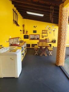 a room with a yellow wall with a table and a wooden table at Casa Conforto & Lazer Foz do Iguaçu in Foz do Iguaçu
