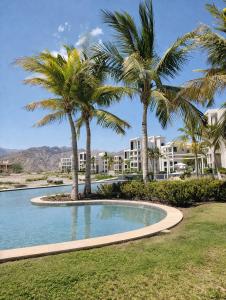 a pool with palm trees in front of a building at Manzar View - Private Rooftop Dining & Epic Views in As Sīfah