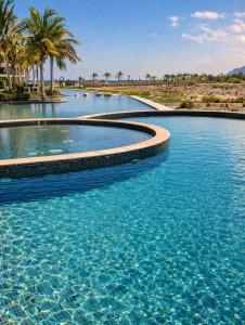 a swimming pool with blue water and palm trees at Manzar View - Private Rooftop Dining & Epic Views in As Sīfah