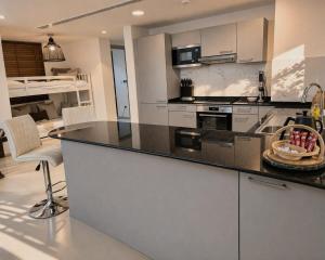 a kitchen with white cabinets and a black counter top at Manzar View - Private Rooftop Dining & Epic Views in As Sīfah