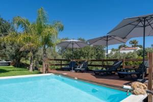 a swimming pool with patio furniture and umbrellas at Spacious & Artistic House with Pool by HostWise in Moncarapacho