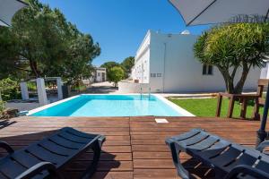 a swimming pool with two chairs and an umbrella at Spacious & Artistic House with Pool by HostWise in Moncarapacho +58 photos