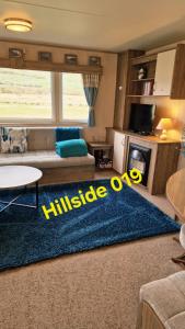 a living room with a couch and a blue rug at Lyons Sunnysands - Hillside 019 in Barmouth