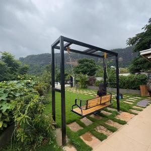 a person sitting on a swing in a garden at Misty Falls Karjat Waterfall view in Jambrung 