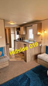 a room with a kitchen and a living room with a table at Lyons Sunnysands - Hillside 019 in Barmouth