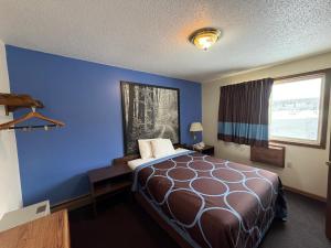 a hotel room with a bed and a blue wall at Iron Mountain Inn & Suites MI US 2 in Iron Mountain