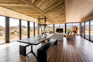 a living room with a table and a couch at Iconic 7,000sf Glass Villa with 2 Pools on 350 Acres in Pioneertown