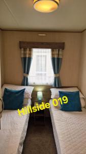 two beds in a room with a window at Lyons Sunnysands - Hillside 019 in Barmouth