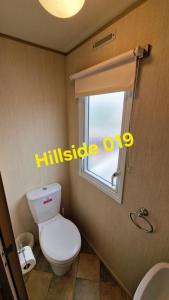 a bathroom with a white toilet and a window at Lyons Sunnysands - Hillside 019 in Barmouth +11 photos