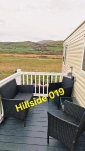 a deck with two wicker chairs and a pair of scissors at Lyons Sunnysands - Hillside 019 in Barmouth