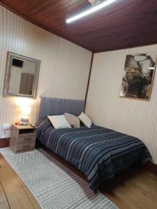 a bedroom with a bed and a night stand with a lamp at Puerto sureño in Puerto Montt