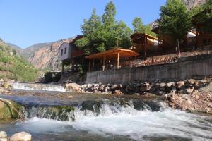 a resort with a waterfall next to a river at Kapuzbaşı Şelaleleri Uçar pansiyon in Büyükçakır
