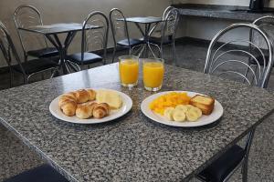 two plates of food on a table with two glasses of orange juice at Hotel Royal - Rubiataba in Rubiataba