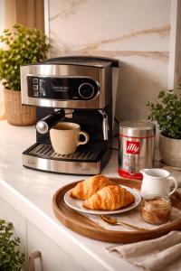 a coffee maker with a plate of croissants and coffee cups at Ohana Boutique Málaga Centro in Málaga +2 photos