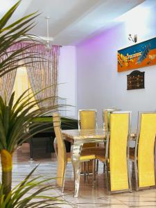 a dining room with a table and yellow chairs at Bold 3 Bedroom Apartments in Abuja