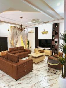 a living room with brown furniture and a large screen tv at Bold 3 Bedroom Apartments in Abuja