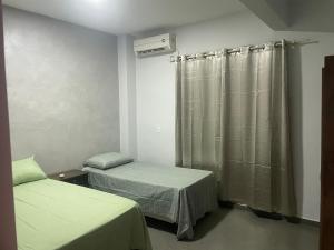 a room with two beds and a window with curtains at Residencial Mandi in Guaíra