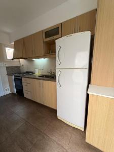a white refrigerator in a kitchen with wooden cabinets at Cabaña Fiorella in Santa Teresita