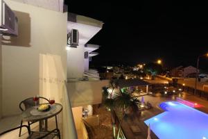 a balcony with a view of a swimming pool at night at Sidari Vibes Aparthotel in Sidari