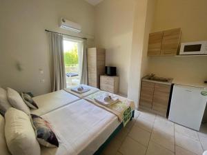 a bedroom with a large white bed and a kitchen at Sidari Vibes Aparthotel in Sidari