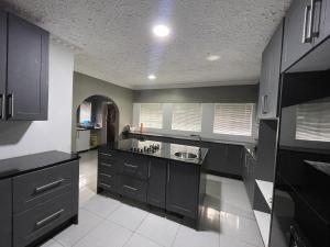 a kitchen with black cabinets and white tile floors at Alamaison in Umtali